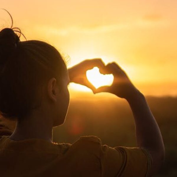 Woman Sitting While Showing Heart Sign Hands